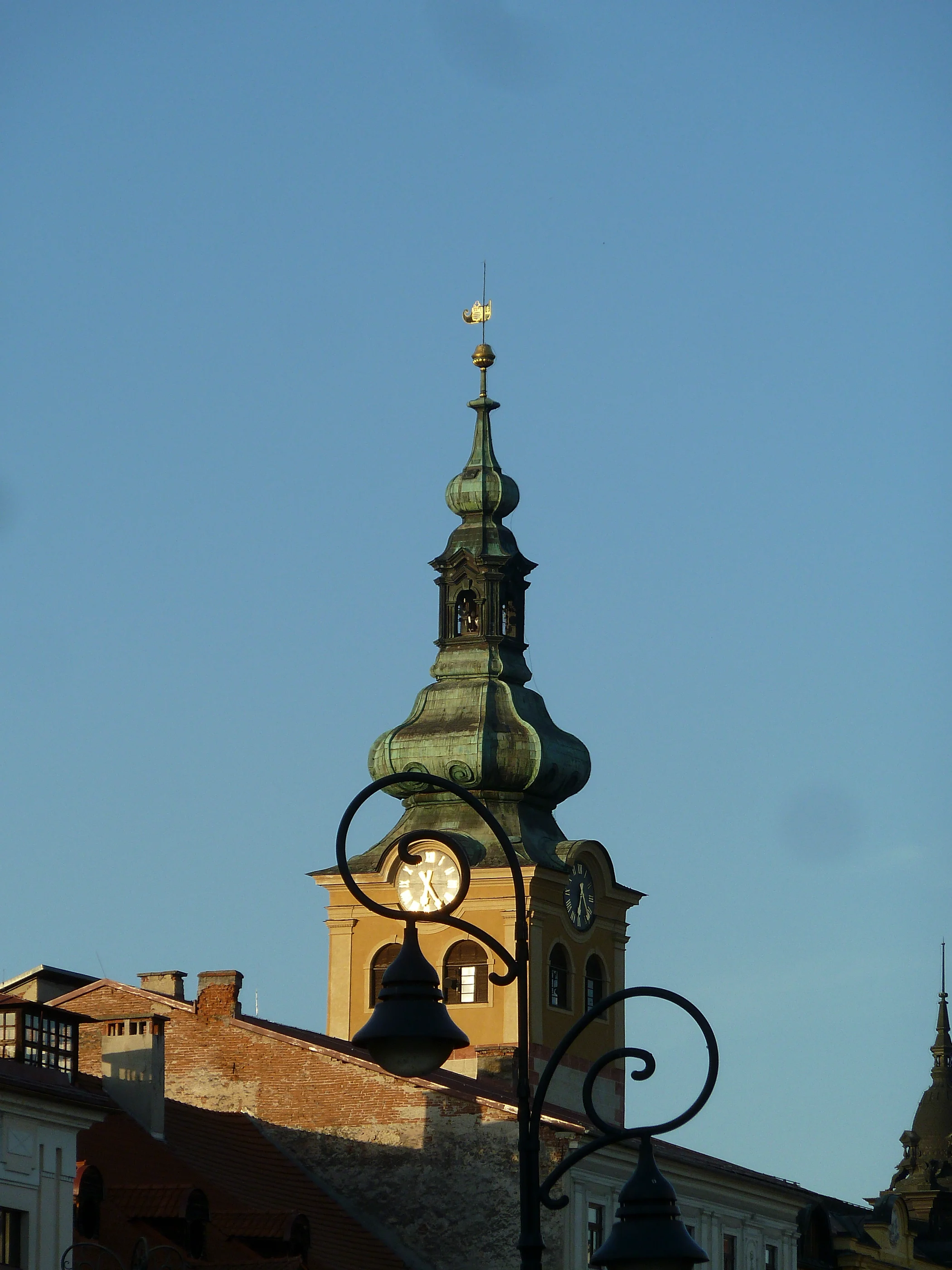An ornate tower with a green dome beside a street lamp